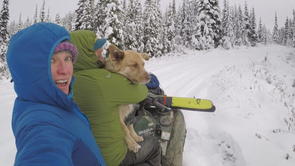 2 people and a dog on a quad going backcountry skiing